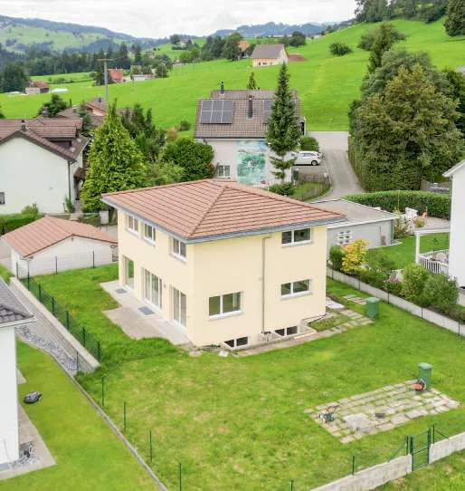 Einfamilienhaus mit Garten in hügeliger Wohnlage aus der Luft